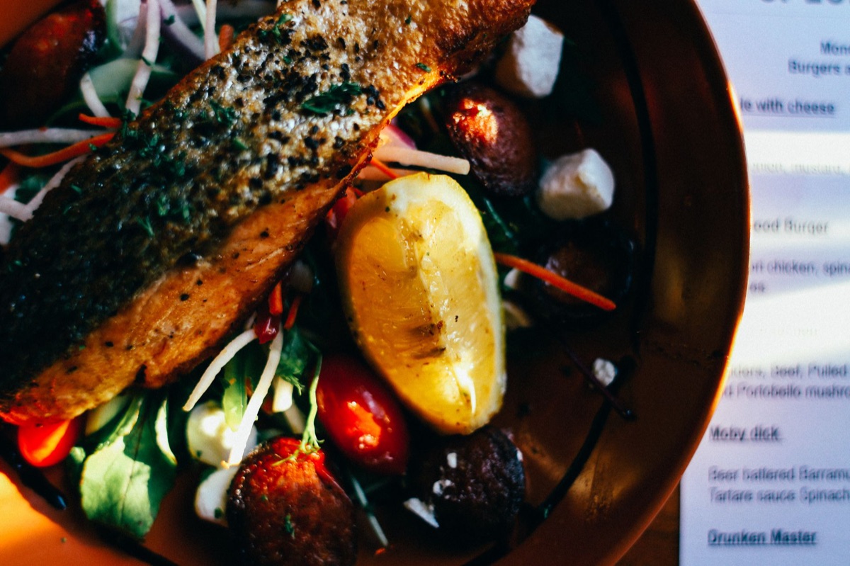 grilled fish with mixed greens on white plate